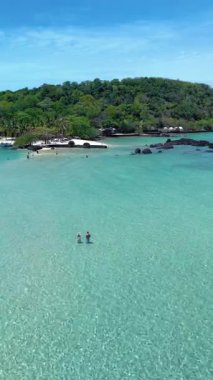 Tayland 'daki Koh Kham Adası' nın dinginliğini deneyin. Kristal berrak suların yemyeşil bitkilerle buluştuğu yer. Ziyaretçiler çarpıcı sahili keşfeder ve sıcak güneşin tadını çıkarırlar..