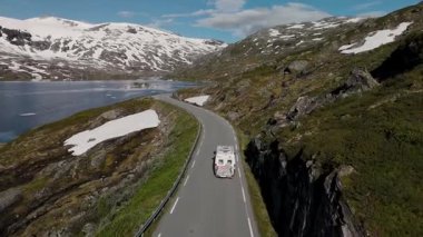 Zengin yeşil tepeler ve karlı tepeler parlak mavi gökyüzünün altındaki bu dolambaçlı yolu kucaklıyor. Norveç 'te bir kampçı göl kenarındaki büyüleyici manzaralarda dolaşırken bir macera yaşanıyor..