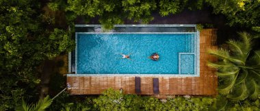 Yukarıdan çekilen sakin bir anda, iki kişi güzel bir turkuaz havuzda dinleniyor. Yengeç Tayland 'da yemyeşil bir havuzda.