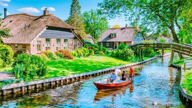 20 Mayıs 2020 'de Hollanda' nın Giethoorn şehrinde bereketli yeşilliklerle çevrili sakin geleneksel evler sergileniyor. Ziyaretçiler, Kuzey Venedik olarak bilinen bu pitoresk köyde kayıkla gezmenin keyfini çıkarıyorlar..