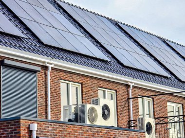 Hollanda 'da çağdaş bir konuta, şık güneş panelleri içeren bir hava kaynağı ısı pompası kurulumu. Bu kurulum sürdürülebilir enerji çözümlerini ve modern tasarımı vurgular.