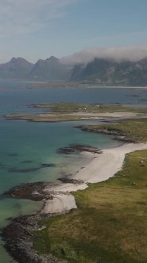 Norveç kıyı şeridinin nefes kesici güzelliğini keşfedin, el değmemiş beyaz kumlu plajlar, durgun turkuaz sular, ve Lofoten Norveç 'in görkemli dağ arkaplanlarına kurulmuş yemyeşil tepeler.