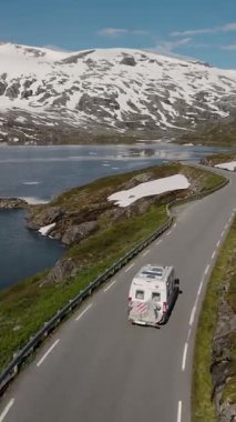 Norveç 'te bir karavanın çarpıcı dağlar ve parlak göllerle çevrili virajlı yollarda seyahat etmesinin heyecanını yaşayın. Langvatnet Gölü boyunca Norveç Ulusal Yolu 15.