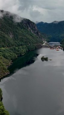 Norveç 'te yeşil dağlarla çevrili sakin bir fiyordun nefes kesici manzarası. Durgun sular bereketli manzarayı mükemmel yansıtıyor, doğa severler için ideal huzurlu bir atmosfer yaratıyor..