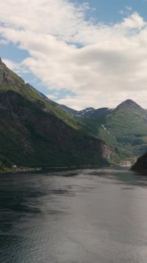 Engebeli dağların sakin sular üzerinde dramatik bir şekilde yükseldiği Norveç fiyortunun nefes kesici güzelliğini deneyimleyin..