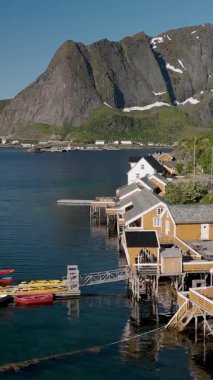 Norveç 'in güzelliğini, görkemli dağlar ve sakin sularla çevrili altın güneş ışığıyla yıkanmış büyüleyici sahil kulübeleriyle yaşayın. Sakrisoy, Moskenes, Lofoten adaları. Norveç.
