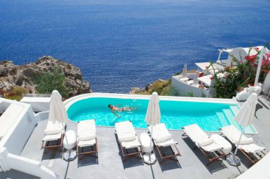 Bir tatilci, sahil köşkündeki güzel bir turkuaz havuzda ferahlatıcı bir yüzüşten zevk alır..