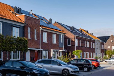 Yeni inşa edilmiş binalar çatılarda parlak siyah güneş panelleri sergiliyor. Açık mavi gökyüzü yeşil enerji girişimlerinin altını çizerek canlı bir mahalle oluşturuyor..