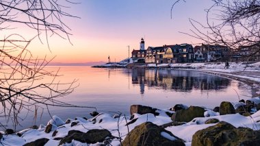 Urk, Hollanda, sakin bir göl köyünde sıcak bir parıltı, sakin sulara yansıyan büyüleyici eski binalar sergiliyor. Kar kıyı şeridini süslüyor, bir kış harikalar diyarı oluşturuyor..