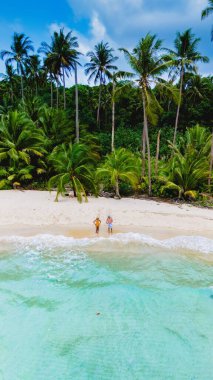 Huzurlu bir plaj sahnesi, canlı palmiyelerle çevrili yumuşak kumun üzerinde duran bir çiftle başlar. Koh Kood Tayland adasında tatilde olan çift.