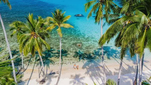 Temiz mavi bir gökyüzünün altında sallanan palmiyelerle çevrili el değmemiş bir sahil boyunca bir çift yürüyüş. Kristal berraklığında su parıldıyor, Koh Kood Tayland 'da rahatlık ve neşe uyandırıyor.