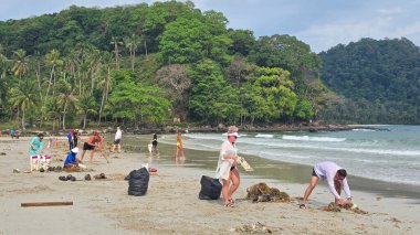 Koh Kood, Tayland, 13 Mart 2025, kendini adamış gönüllüler, doğal güzelliğin tadını çıkarırken, bir plaj temizliğine katılıp, atıkları, çöpleri ve plastik atıkları temizliyorlar..