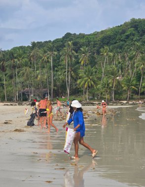 Koh Kood, Tayland, 13 Mart 2025, yerel halk ve ziyaretçiler sahili temizlemek için el ele tutuşuyor, doğayı korumaya olan bağlılıklarını gösterirken çarpıcı ortamın ve sıcak havanın tadını çıkarıyorlar..