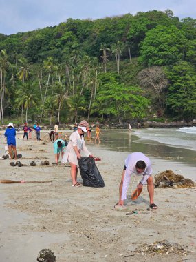 Koh Kood, Tayland, 13 Mart 2025. Gönüllüler plaj temizliğine katılmak için kumlu kıyılarda toplanıyorlar. Güneş, onlar çöp ve döküntü toplarken parlıyor.