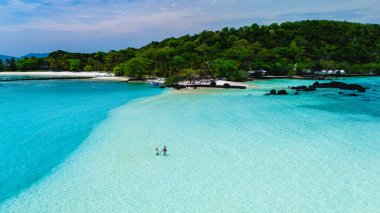 Turkuaz sular ve beyaz kumlu kıyılar Koh Mak Tayland Adası 'nda güneşin tadını çıkaran iki ziyaretçiyi çevrelemektedir. Bereketli yeşillik, gevşemek için mükemmel, cennet gibi tropikal cenneti tamamlar..