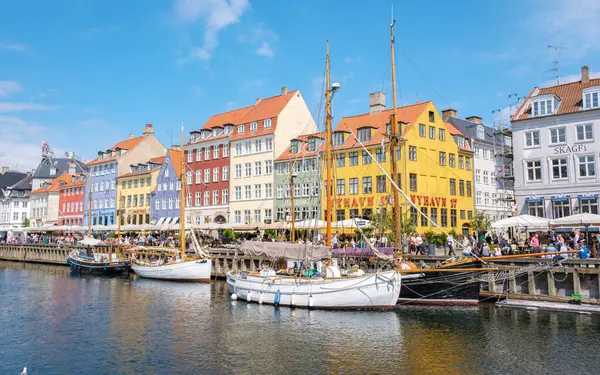 Nyhavn, Kopenhag, Danimarka, 12 Temmuz 204: büyüleyici, renkli binaların kanalı kapladığı yer. Yelkenliler suyu dolduruyor, ziyaretçileri güneşli bir günde bu güzel yerin tadını çıkarmaya çağırıyorlar..