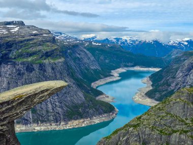 Sakin mavi suların üzerinde yükselen yüksek uçurumların görkemli manzarayı yansıttığı Norveç fiyortlarının çarpıcı güzelliğini deneyimleyin. Norveç 'te Trolltunga yürüyüşü