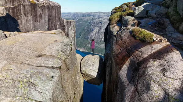 Norveç, Kjeragbolten Lysefjord 'da bir kayanın üzerinde duran yalnız bir gezgin görkemli Lysefjord' a bakıyor..