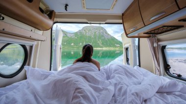 Bir gezgin, karavandan sakin bir sabah geçirir, nefes kesici dağlara ve Lofoten Norveç 'in sakin sularına bakar. Sıcak atmosfer macera ve rahatlamaya davetiye çıkarıyor..