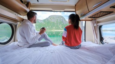 Bir çift rahat bir karavanda dinleniyor, kahveyi yudumlarken aynı zamanda çarpıcı dağları ve Norveç 'te sakin bir gölü seyrediyor. İlham arayan gezginler ve gezginler için mükemmel..