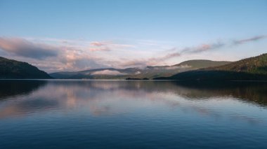 Sabah ışığı Norveç 'teki bir gölün sakin sularına huzur dolu bir ışık saçıyor. Etrafındaki tepelerden yavaşça sis yükselir. Rahatlamak ve ilham vermek için mükemmel sakin bir atmosfer yaratır..
