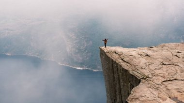 Cesur maceracılar Preikestolen 'in uçurumunda dikiliyorlar, Norveç' teki büyüleyici fiyorda yukarıdan bakıyorlar.