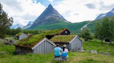 Ziyaretçiler, görkemli dağlar ve gür yeşilliklerle çevrili geleneksel Norveç çiftliklerinin nefes kesici manzarasının keyfini çıkarıyorlar. Innerdalen Norveç 'e yürüyüş yapan bir çift.