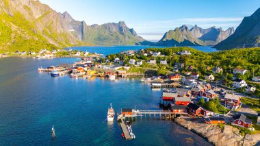 Görkemli dağlar ve sakin bir deniz arasında yer alan Lofoten Norveç 'teki bu renkli kıyı köyünde klasik İskandinav mimarisi sergileniyor. Mavi gökyüzünün altında yavaşça sallanan tekneler.