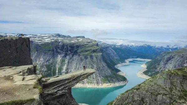 Göz kamaştırıcı manzara Norveç 'in Trolltunga yürüyüşünün ihtişamını yansıtıyor. Maceracılar kayalıkların tepesinde dururlar, derin bir fiyorda bakarlar yemyeşil dağları ve uzak karları olan..