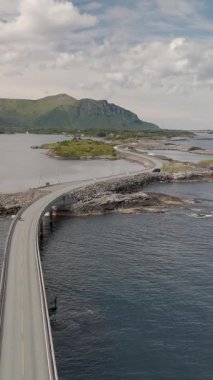 Norveç Atlantik Yolu 'nun güzelliğini tecrübe edin, sahil şeridinde zarafetle süzülüyor. Bu büyüleyici manzara nefes kesici dağları, sakin suları ve dingin gökyüzünün altında yemyeşil suları barındırır..