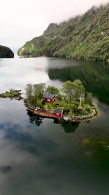 Küçük bir adada yuva yapmış güzel bir kulübe Norveç fiyortunun sakin sularını yansıtır. Lovrafjorden Norveç