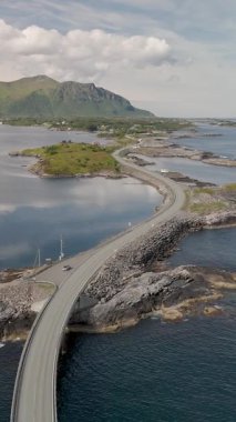 Norveç kıyı şeridi boyunca kayalık oluşumlar ve sakin sularla dokuma yapan görkemli otoyol. Çevresindeki tepelerin ve uzak manzaraların nefes kesici manzarası, Atlantik Okyanus Yolu Norveç