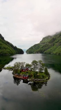 Huzurlu bir adaya kurulmuş, sakin sulara bakan büyüleyici kırmızı bir kulübe. Etrafı yemyeşil yemyeşil ve muhteşem fiyortlarla çevrili. Lovrafjorden, Norveç