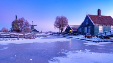 Güneş güzel bir köyün üzerinde batarken, geleneksel Hollanda evlerinin saçaklarından sarkıtlar sarkıyor. Zaanse Schans Hollanda