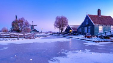 Güneş güzel bir köyün üzerinde batarken, geleneksel Hollanda evlerinin saçaklarından sarkıtlar sarkıyor. Zaanse Schans Hollanda