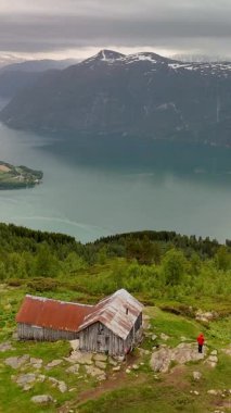 Manzaralı bir manzara Molden Norveç 'te sakin bir fiyorda bakan bir dağ yamacına kurulmuş bir kır kulübesini gözler önüne seriyor..