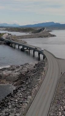 Norveç 'teki Atlantik Yolu' nun karmaşık kıvrımlarına, araçların manzaralı manzaralar ve berrak bir gökyüzünün altında parıldayan sular arasında dolaştığı yere hayret edin..