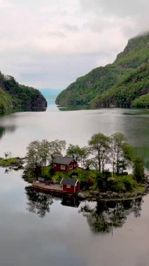 Sakin sularla çevrili küçük bir adada büyüleyici kırmızı bir kulübe. Bereketli yeşil dağlar Norveç 'in doğal güzelliklerini gözler önüne seren fiyortta yansıyor. Lovrafjorden, Norveç