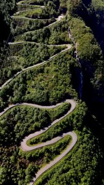 Norveç 'teki canlı yeşil tepelerin arasından oyulmuş, kayalık uçurumlara ve güzel şelalelere, Lysefjord' a, Lysebotn Norveç 'e giden yola karşı güçlü tezatlarla dolu dolambaçlı bir yolun nefes kesici manzarası.