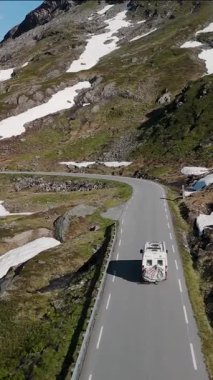 Norveç 'in görkemli manzaralarını keşfedin. Kamp aracı, kar kaplı dağlarla ve yemyeşil alanlarla çevrili virajlı yollarda, Geiranger Trollstigen Langvatnet yolu, 63.