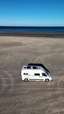 Danimarka 'daki Romo Lakolk Sahili' nin huzurlu güzelliğinin tadını çıkarın. Kamp aracı kumlu sahillerde dolaşıyor. Geniş kıyı şeridi açık mavi gökyüzünün altında uzanır, macera ve rahatlamaya davetiye çıkarır..