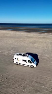 Danimarka 'daki Romo Lakolk plajında sakin bir gün geçirin. Kumlu sahil şeridinde beyaz bir karavan geziyor..