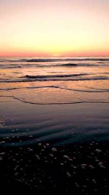 Güneş batarken Danimarka 'daki Romo Lakolk plajının dingin güzelliğine tanık olun. Gökyüzüne canlı renkler saçıyor ve sakin sulara yansıyor. Yumuşak dalgalar barışçıl bir atmosfer yaratır.