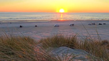 Danimarka 'daki Romo Lakolk plajının sakin sularını aydınlatan nefes kesici günbatımına tanık olun..