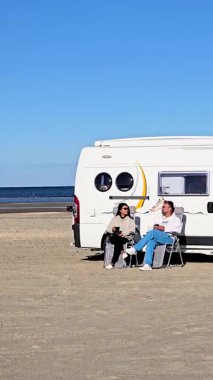 Romo Lakolk plajında güneşli bir günün tadını çıkarın. Arkadaşları karavanın yanında dinleniyor. Altın kumlar huzurlu mavi sulara kadar uzanıyor, Danimarka 'da rahatlama ve kahkaha için mükemmel bir zemin oluşturuyor.