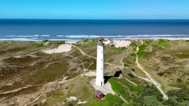 Lyngvig Deniz Feneri 'nin büyüleyici manzarasını keşfedin. Hvide Sande Jutland, Danimarka' da, altın kumların canlı mavi denizle buluştuğu yerde..