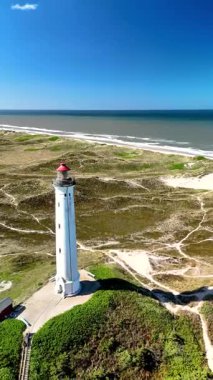 Danimarka 'nın Jutland kentinin büyüleyici manzaralarını keşfedin, ikonik resimli deniz feneri. Huzurlu sahil manzarası ve parlak mavi gökyüzünün altındaki altın kumların tadını çıkar. Lyngvig Deniz Feneri Hvide Sande