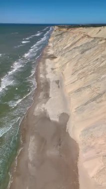 Danimarka 'nın Jutland kentindeki Rubjerg Knude Fyr Deniz Feneri' nin nefes kesici sahil şeridini deneyin. Dalgalar yavaşça kumlu kıyıya vuruyor, heybetli kayalıklar tarafından çerçeveleniyor.