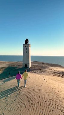 Danimarka 'nın Jutland kentindeki kumlu Rubjerg Knude Fyr Deniz Feneri' nde birkaç gezinti yaparken huzurlu bir an yaşanıyor. İkonik deniz feneri açık mavi gökyüzüne karşı dimdik ayakta duruyor.