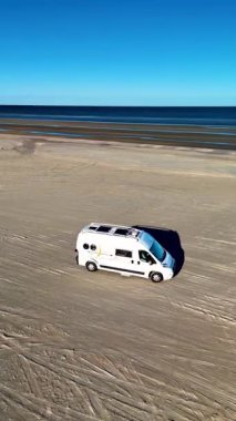 Danimarka 'daki Romo Lakolk Sahili' nde sakin bir gün yaşanıyor. Uçsuz bucaksız açık alanlar ve açık mavi gökyüzüyle çevrili kumlu sahillerde beyaz bir karavan sürüyordu. Gezginleri deniz kıyısından kaçmaya çağırıyordu..